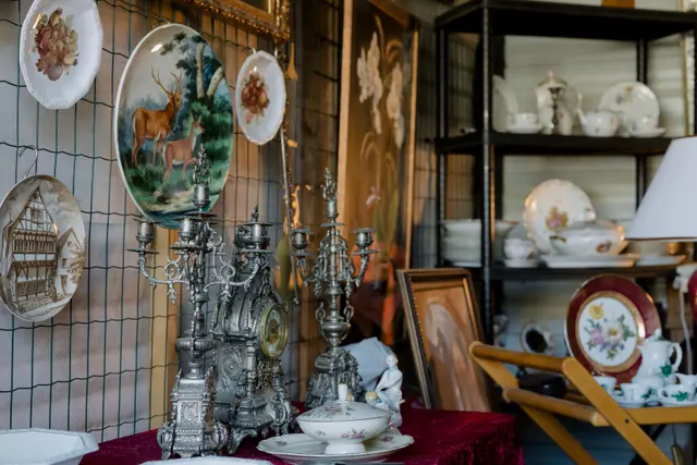 Silver candelabra and a mantel clock staged with hand-painted plates and porcelain