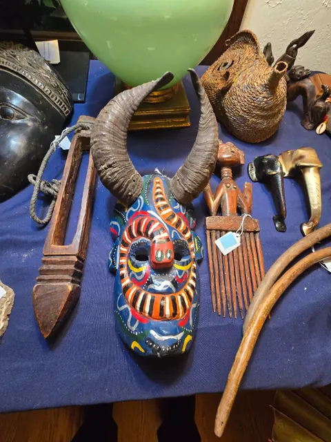 Folk-art horned mask and carved pieces, tagged for sale