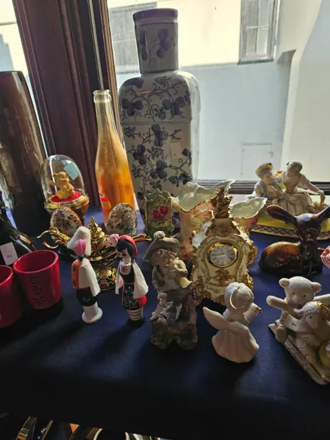 Porcelain, figurines and a gilt clock in the window light